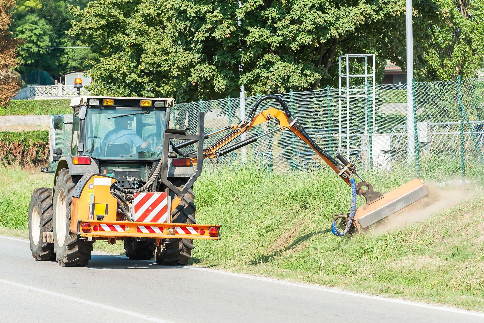 Commercial lawn mower cutting grass on a roadside embankment