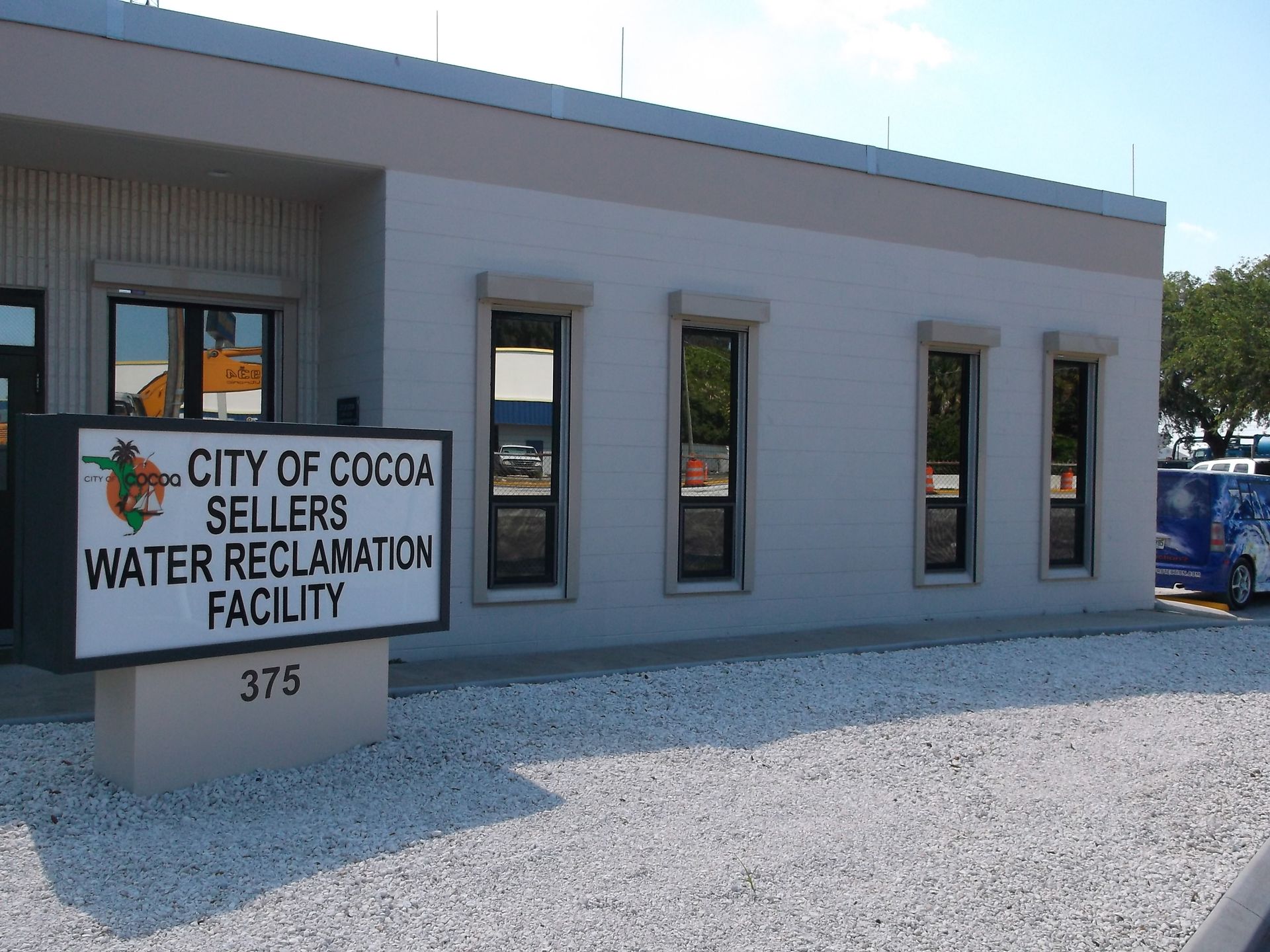 City of Cocoa Sellers Water Reclamation Facility sign beside a gray building and gravel lot