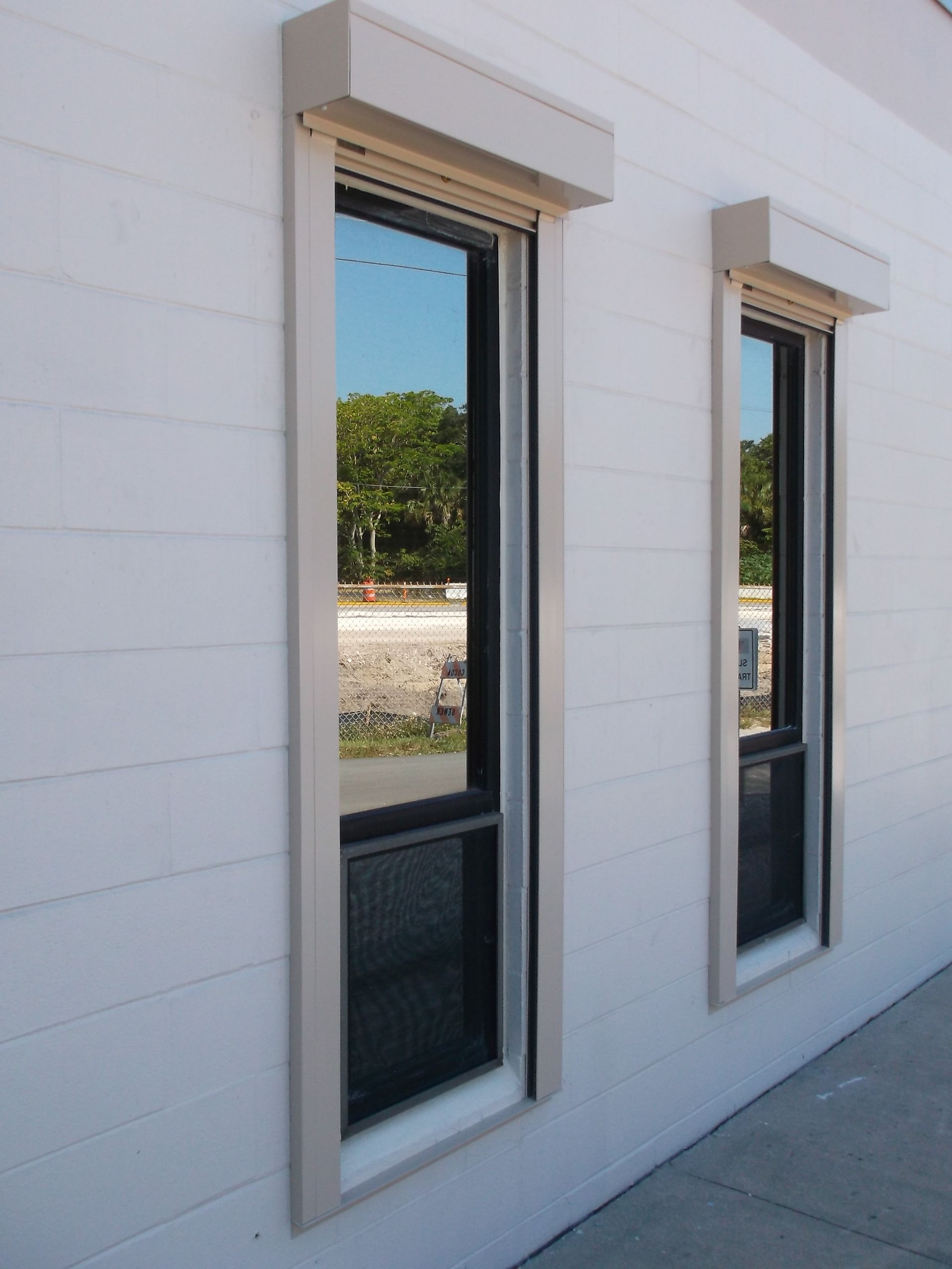 Two narrow black-framed windows on a white exterior wall in bright daylight