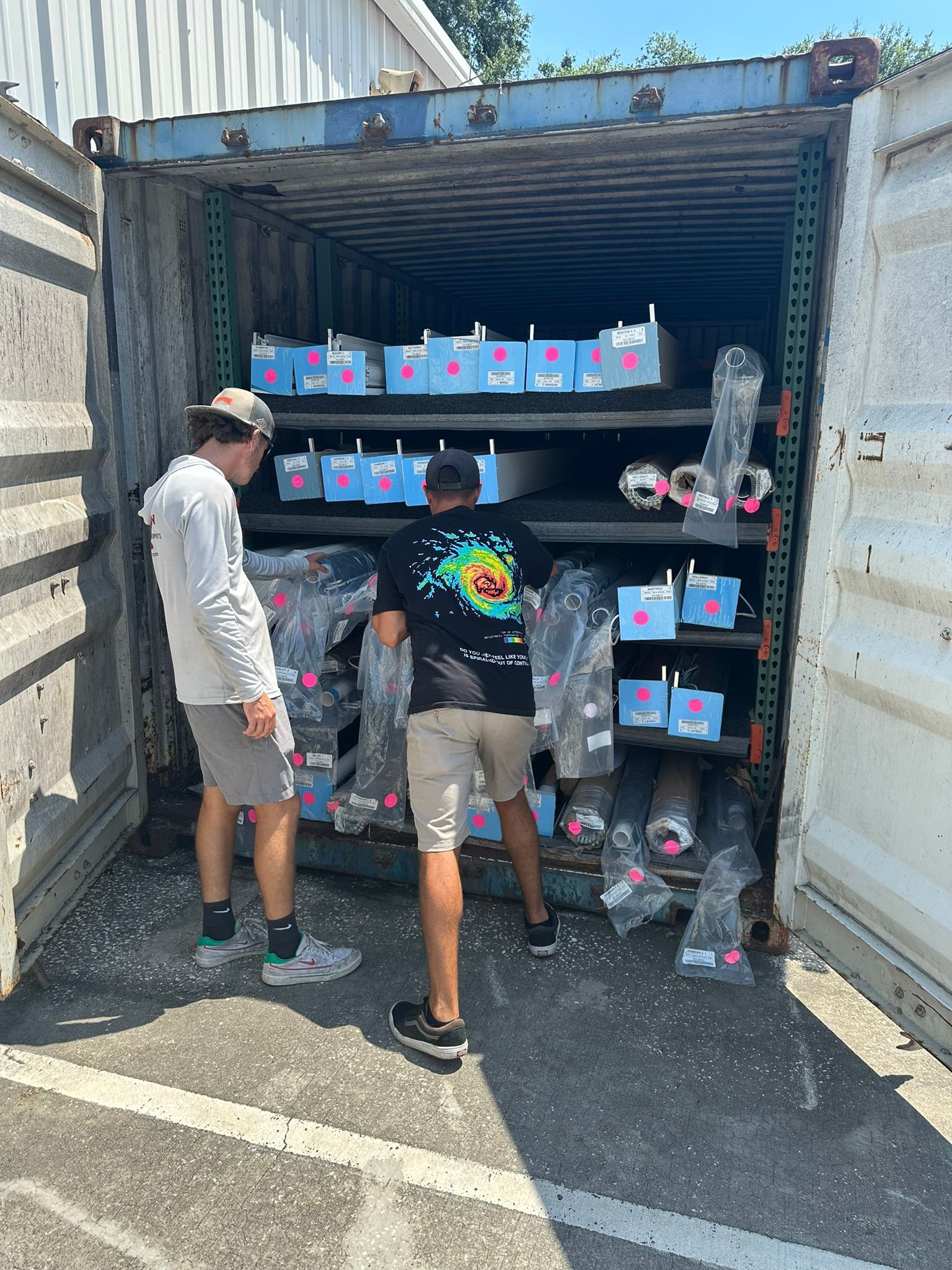 Two people browsing colorful bottled drinks in an open shipping container storefront