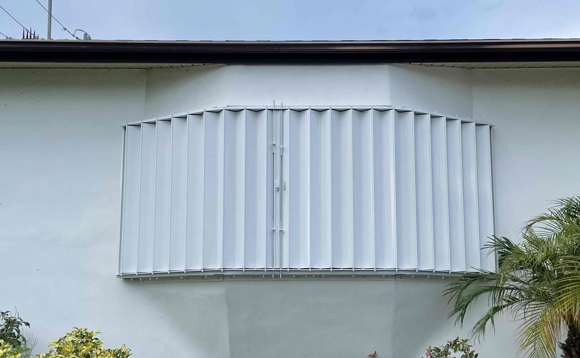 White balcony with vertical slatted railing on a white building facade, seen from outside
