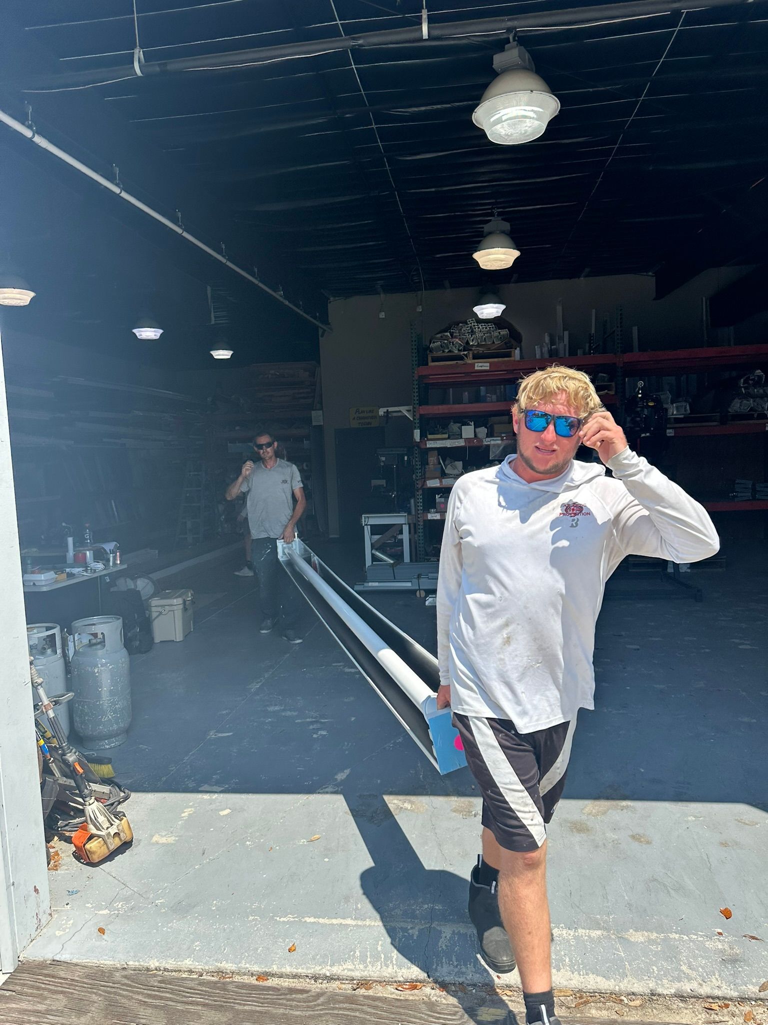 Person in white shirt and sunglasses stands at a garage entrance, adjusting their glasses.