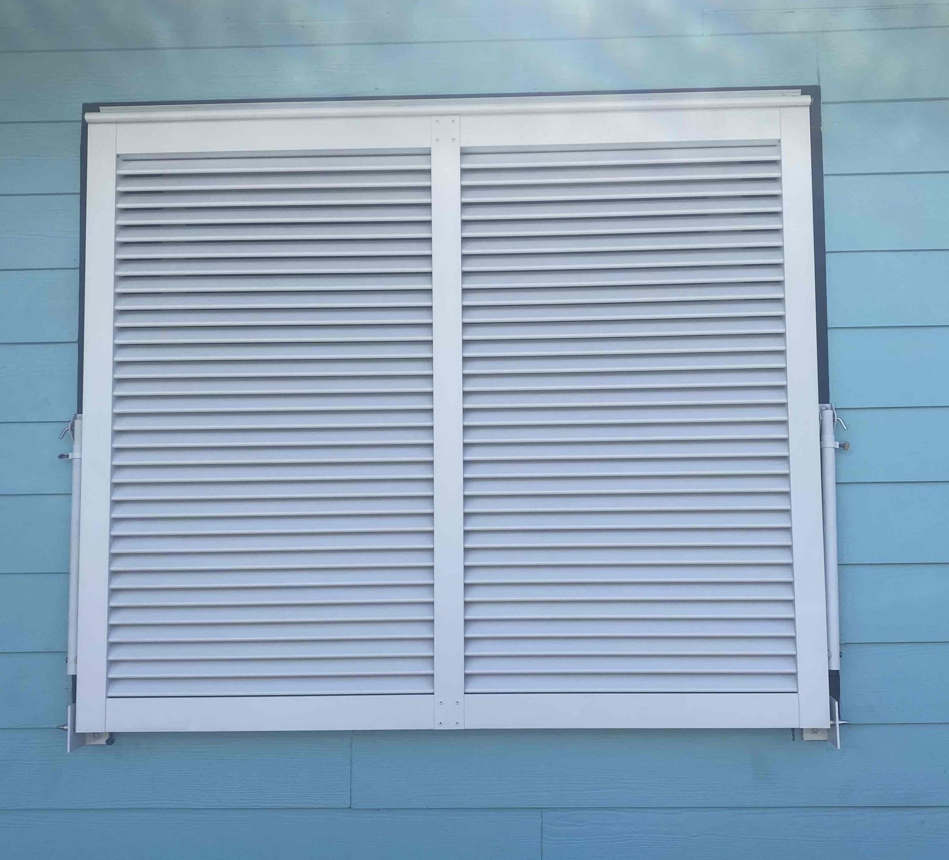 White louvered window shutters on a blue exterior wall