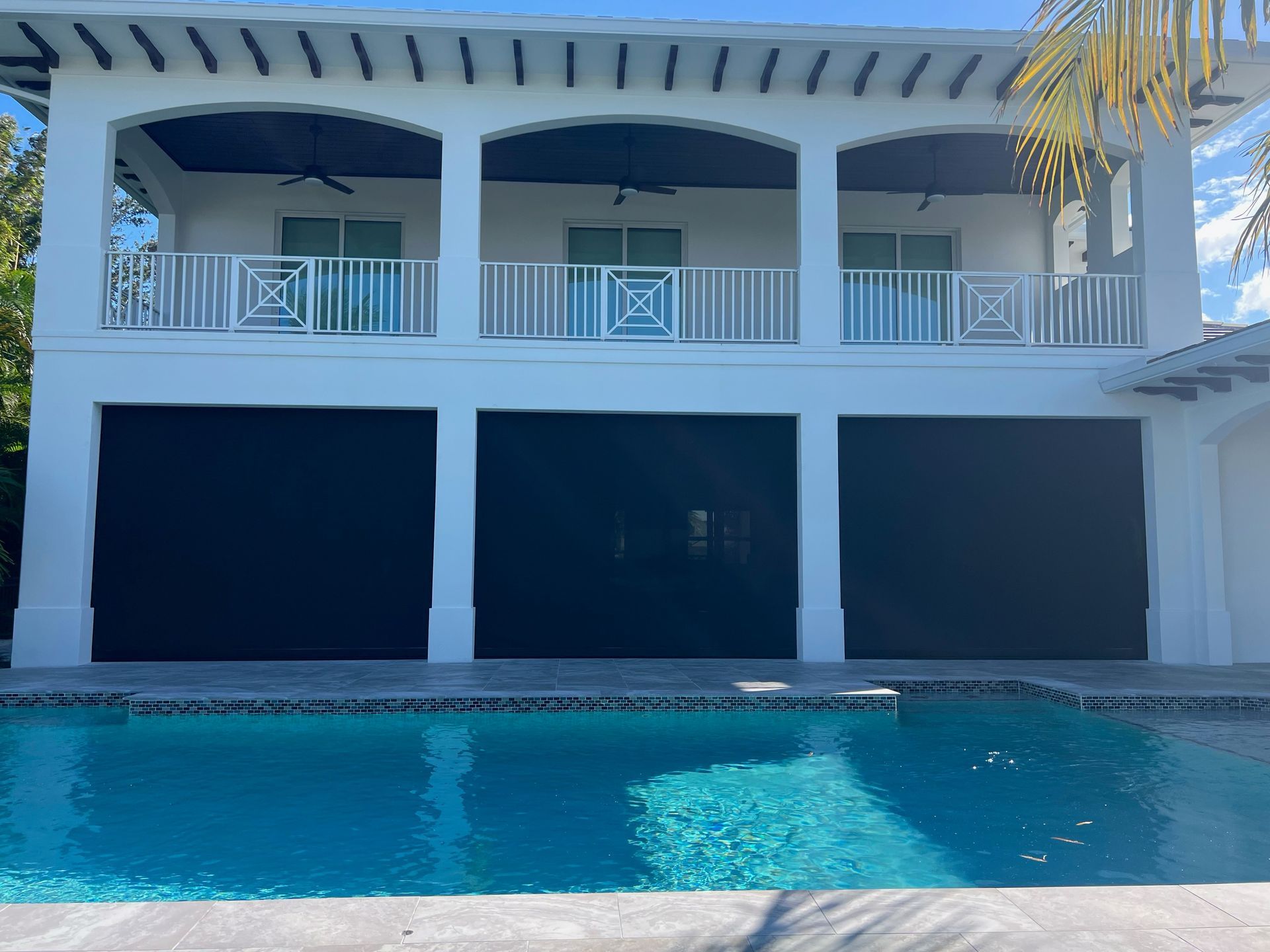 Two-story white house with blue shutters and balcony, overlooking a swimming pool
