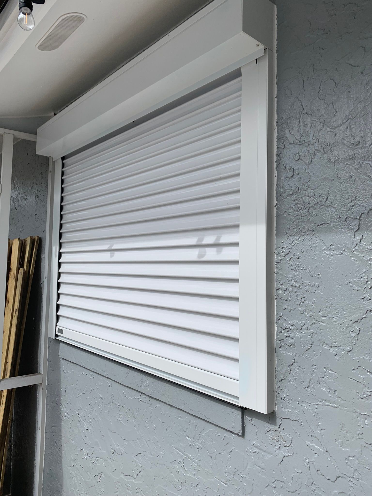Closed white rolling shutter on a gray exterior wall