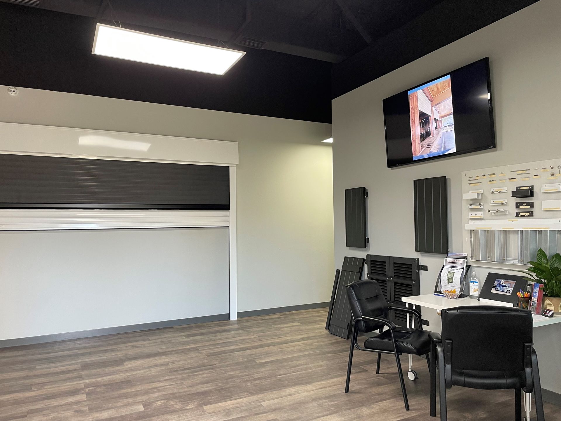 Empty office lobby with desk, chairs, TV, and a closed roll-up door on the left.