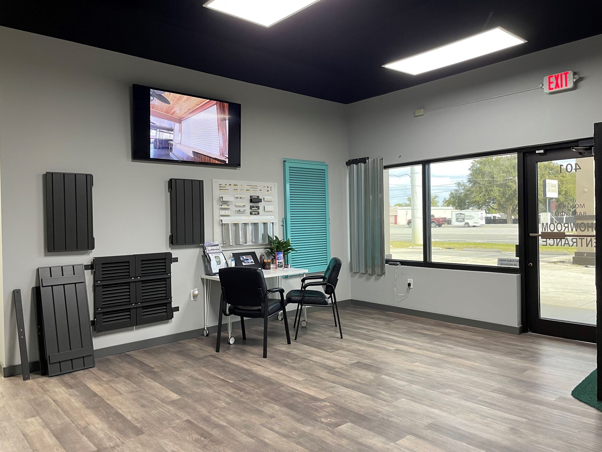 Bright waiting room with chairs, wall-mounted TV, windows, and glass door.