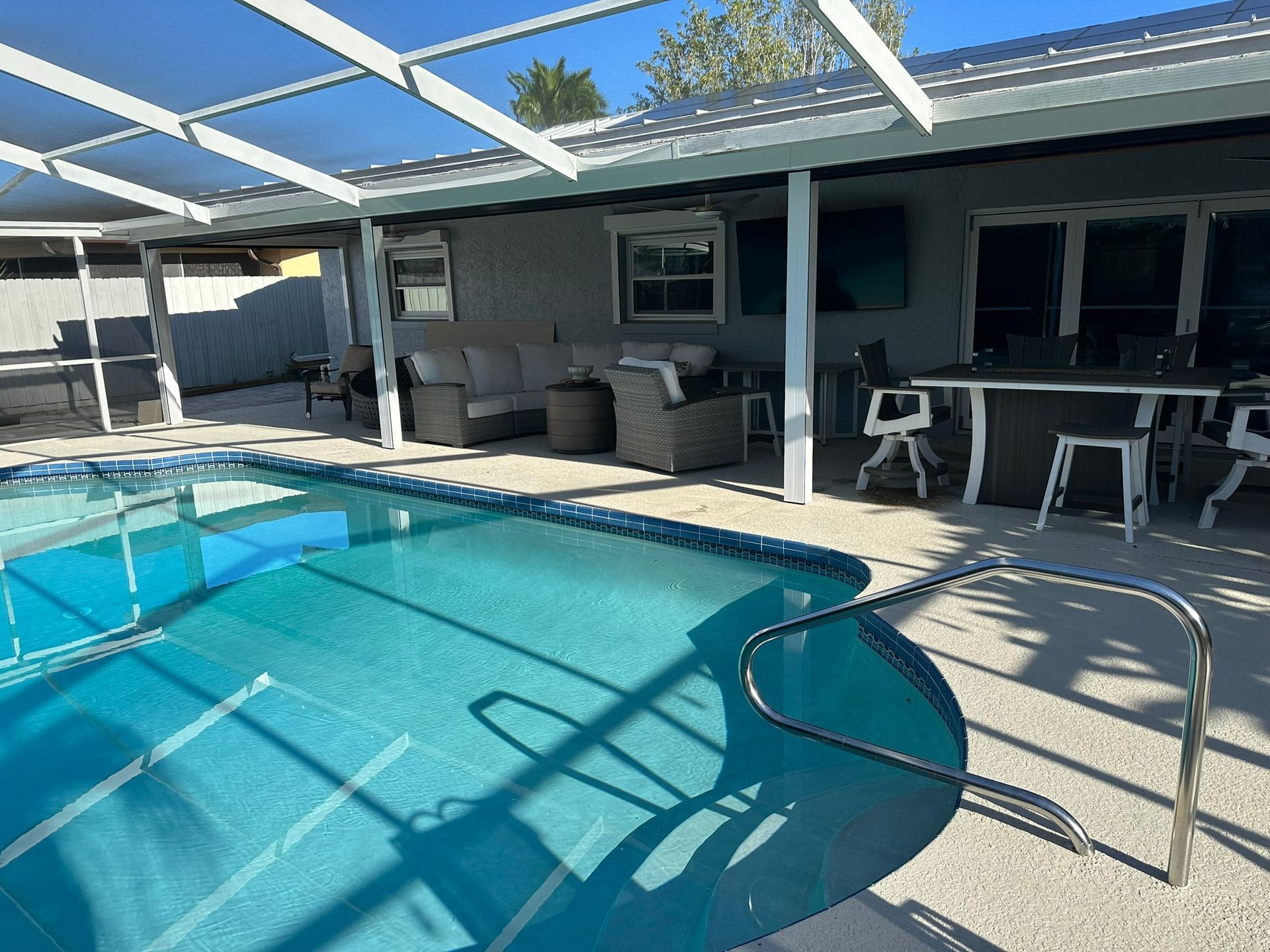 Backyard pool with clear blue water, shaded patio, and outdoor seating