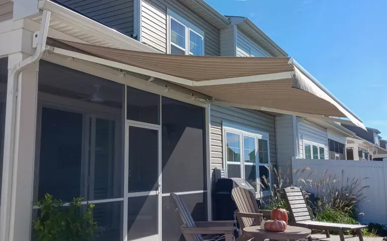 Patio with awning and screened porch outside a two-story house on a sunny day