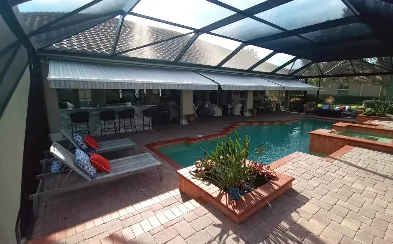 Covered outdoor pool area with brick patio, lounge chairs, and potted plants under a translucent roof