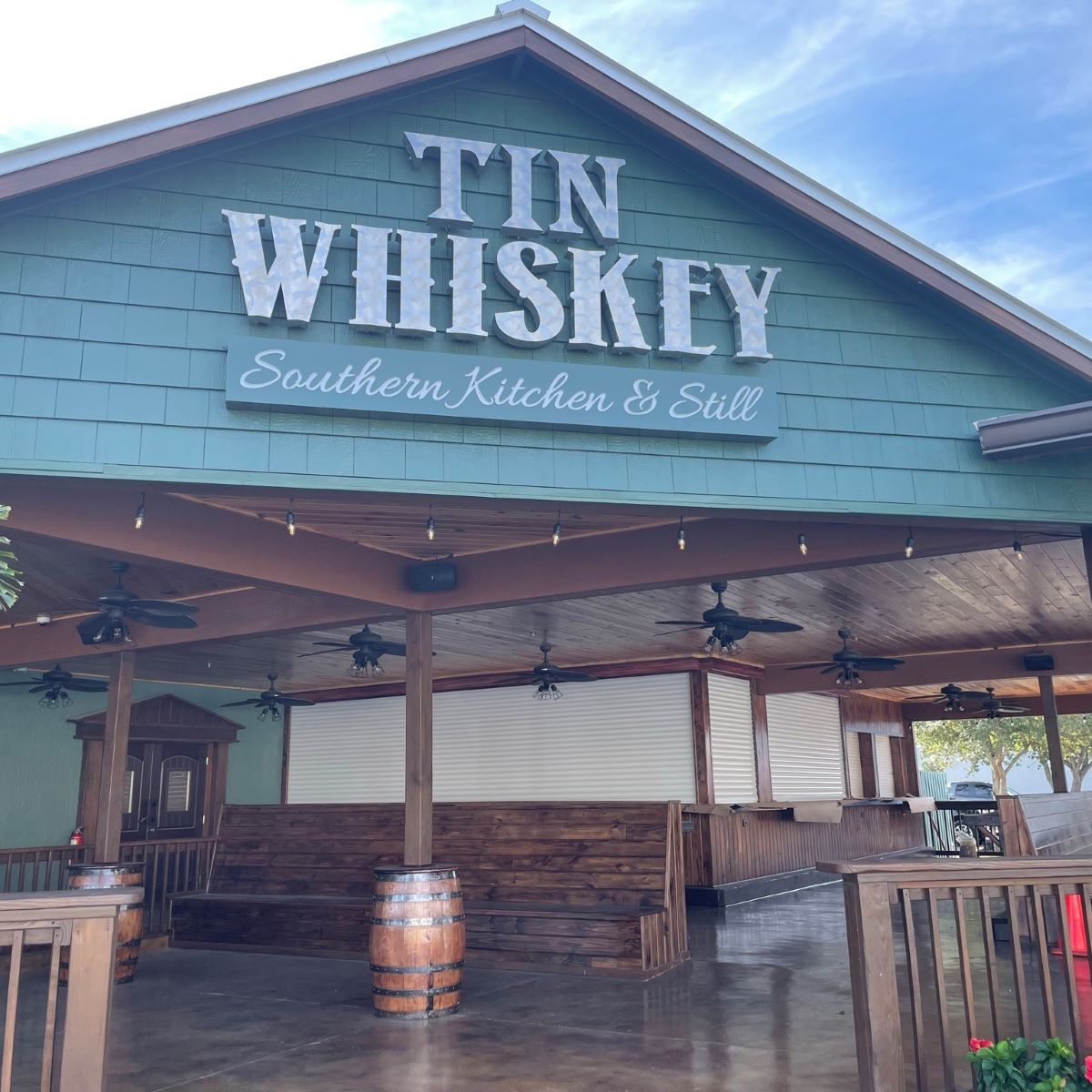 Tin Whiskey Southern Kitchen & Saloon storefront with teal siding and a rustic covered patio.