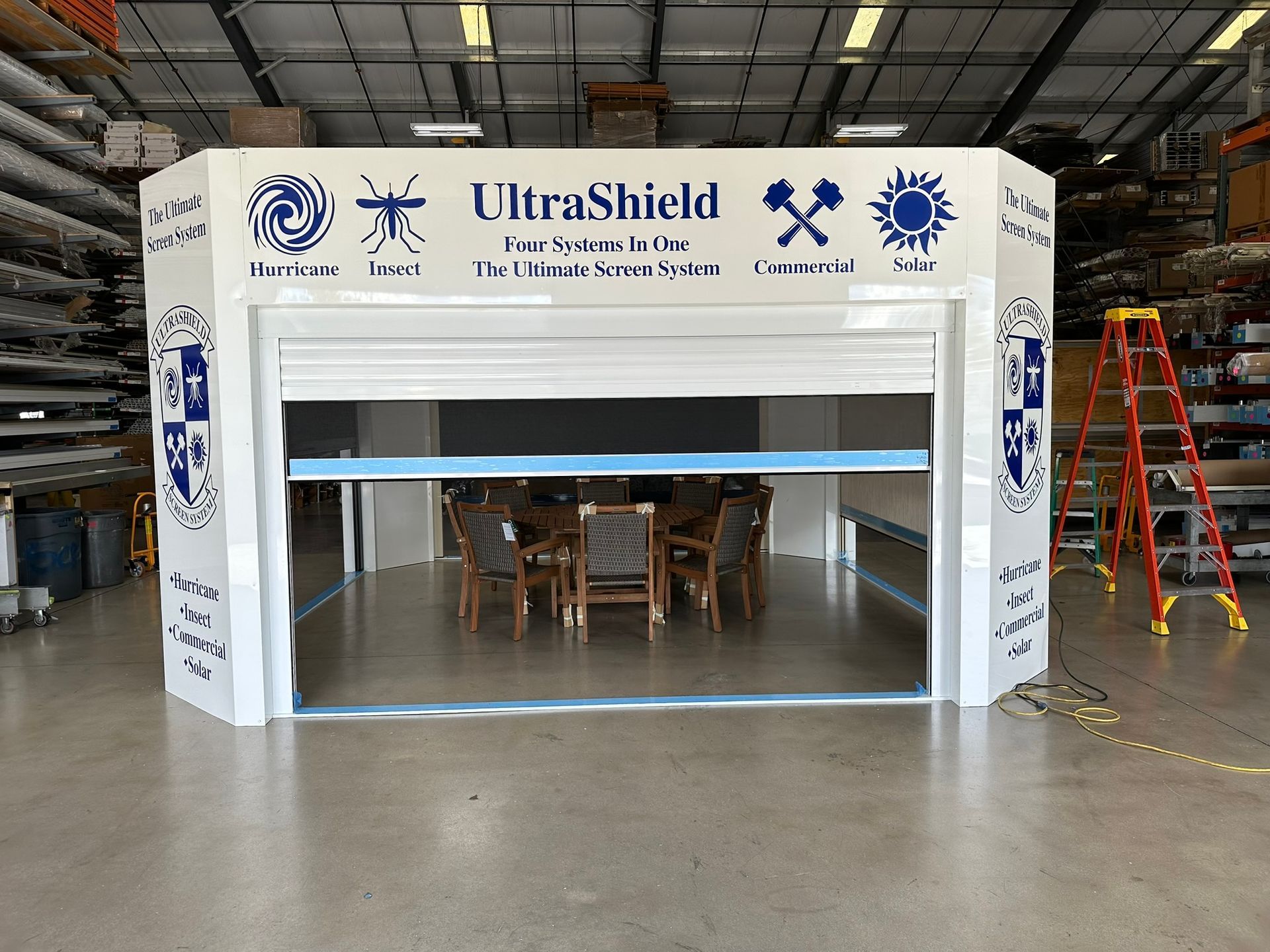 UltraShield portable safety booth in a warehouse, with blue-and-white panels and a large open front.