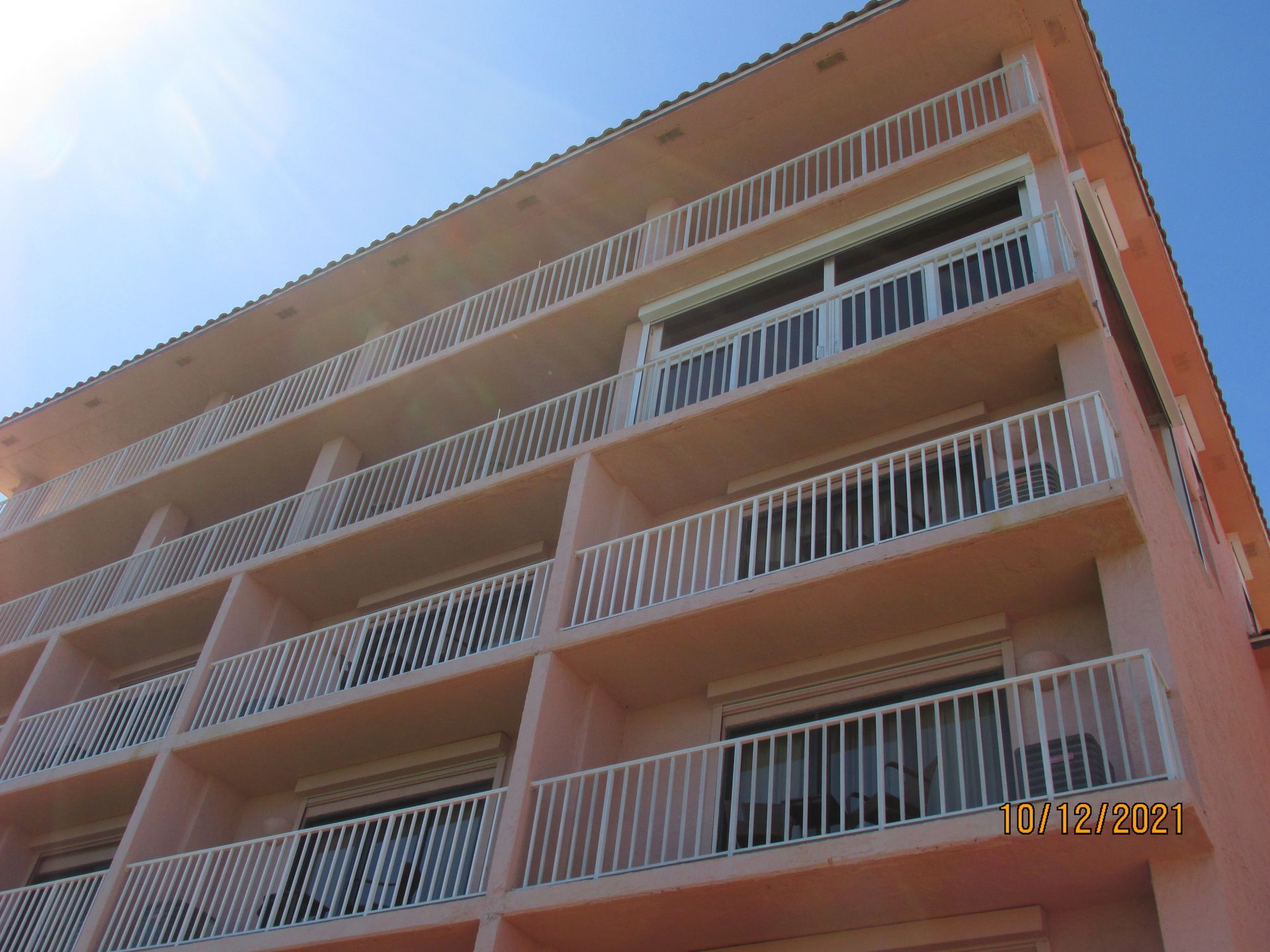 Orange apartment building with white balconies against a clear blue sky
