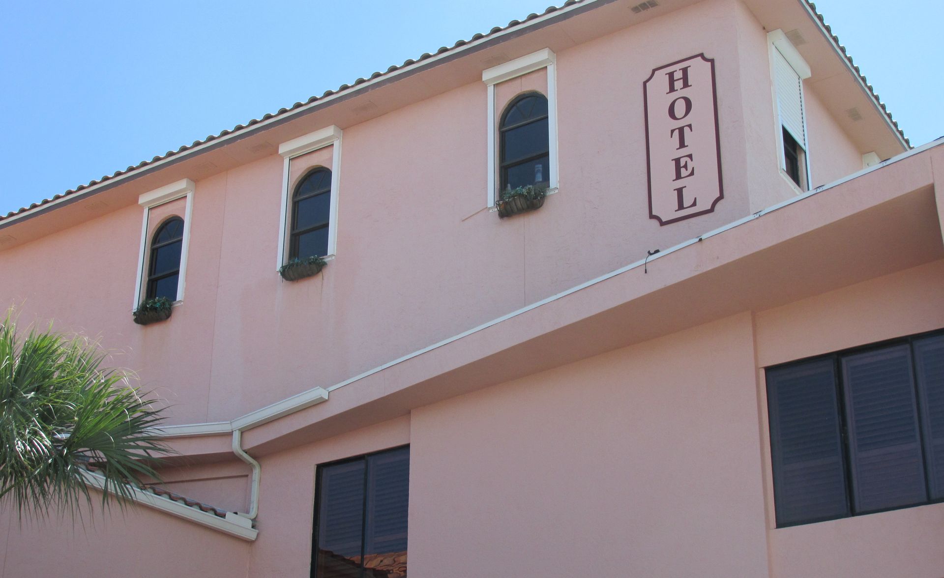 Pink hotel building with arched windows and a vertical HOTEL sign
