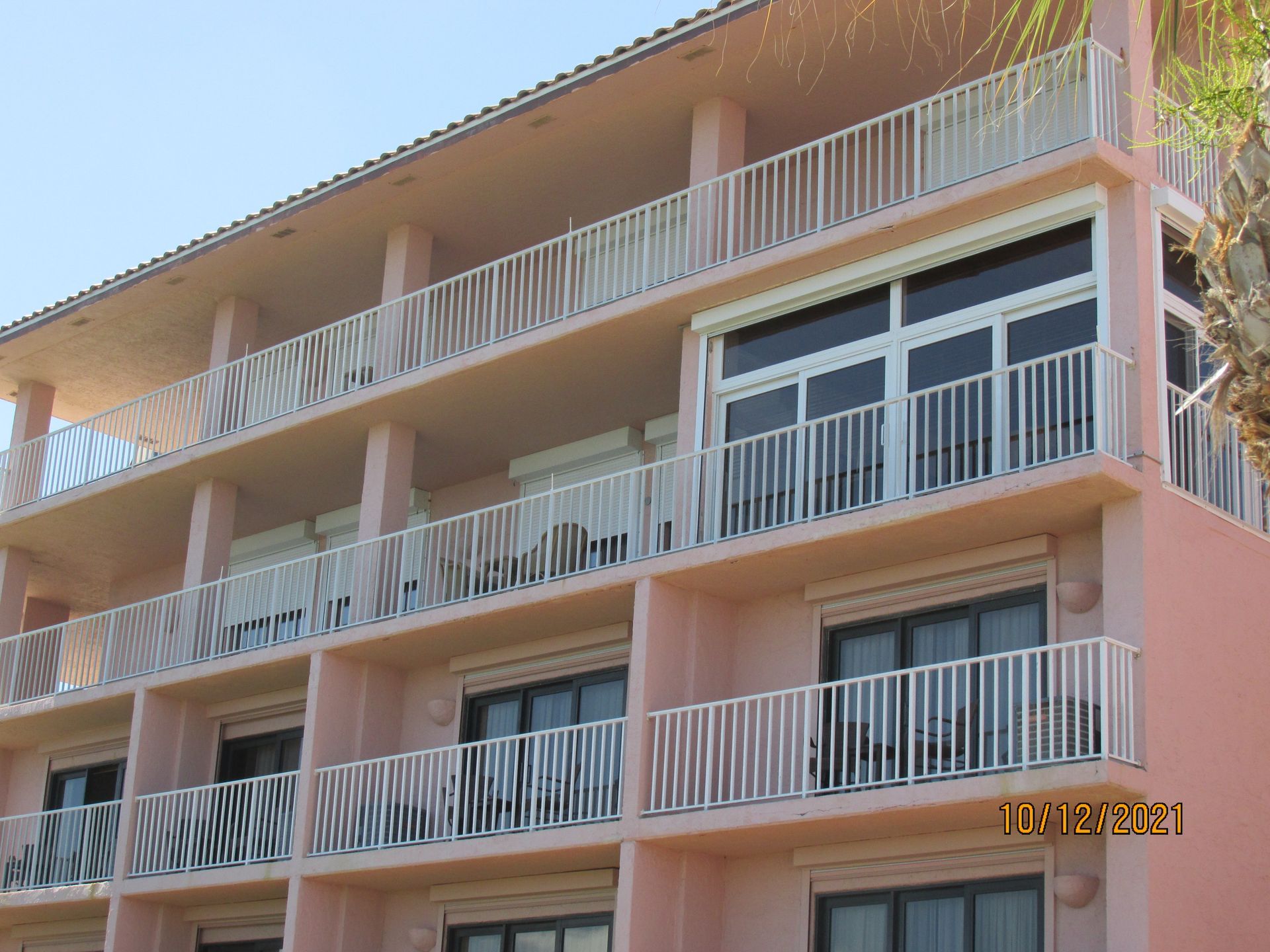 Pink apartment building with white balconies under a clear sky