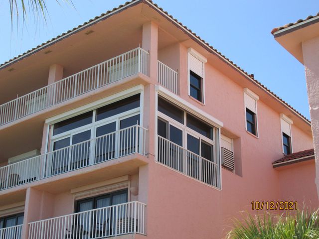 Peach-colored apartment building with white balconies and windows under a blue sky