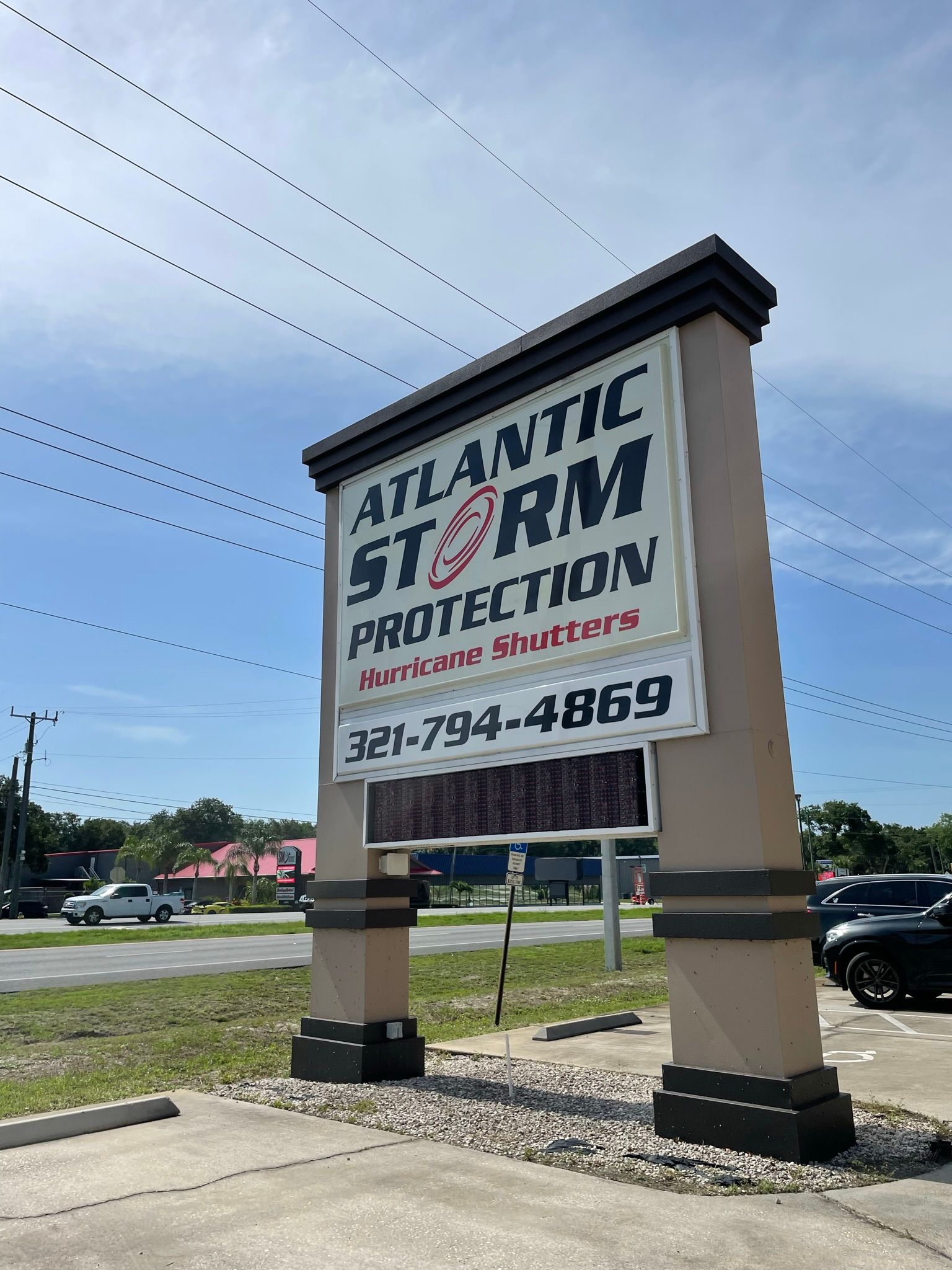 Atlantic Storm Protection roadside sign on a tan monument, with phone number and blue sky background