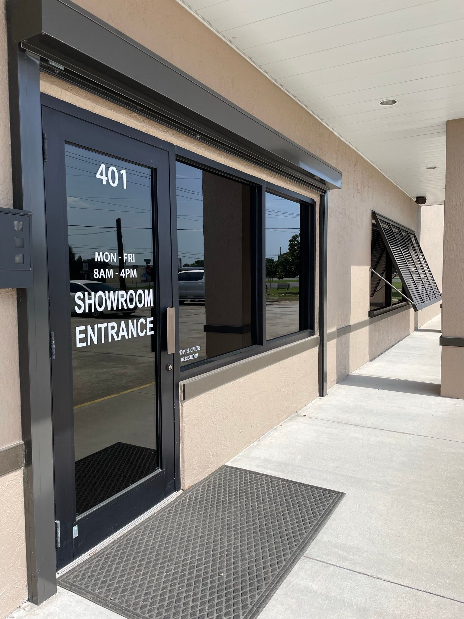 Storefront entrance with glass door marked “401” and “SHOWROOM ENTRANCE” under a covered walkway