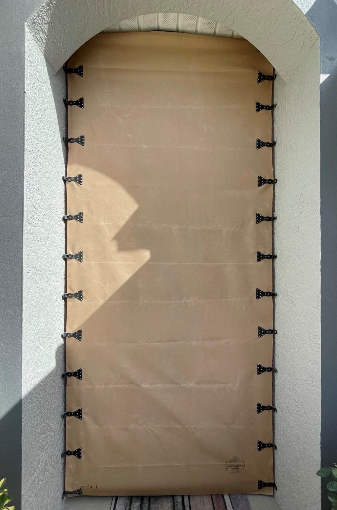 Closed cardboard-covered doorway in a light stone arch, secured with black fasteners on both sides