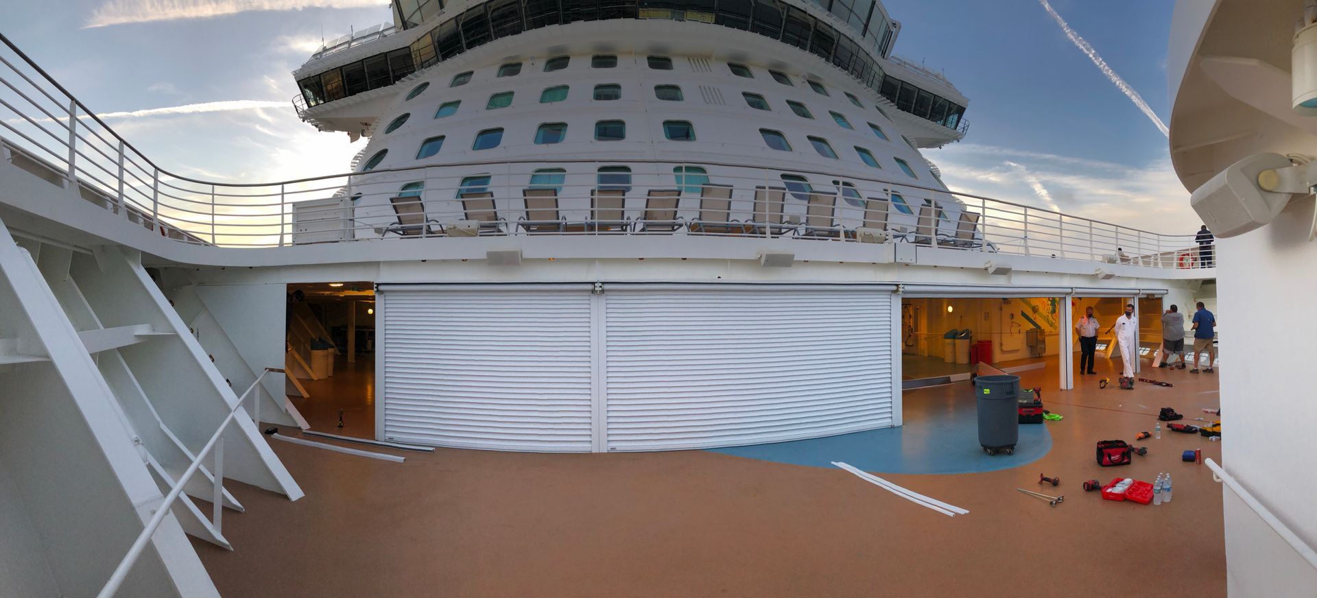 Cruise ship deck with lounge chairs, white canopy, and a curved upper deck under a blue sky