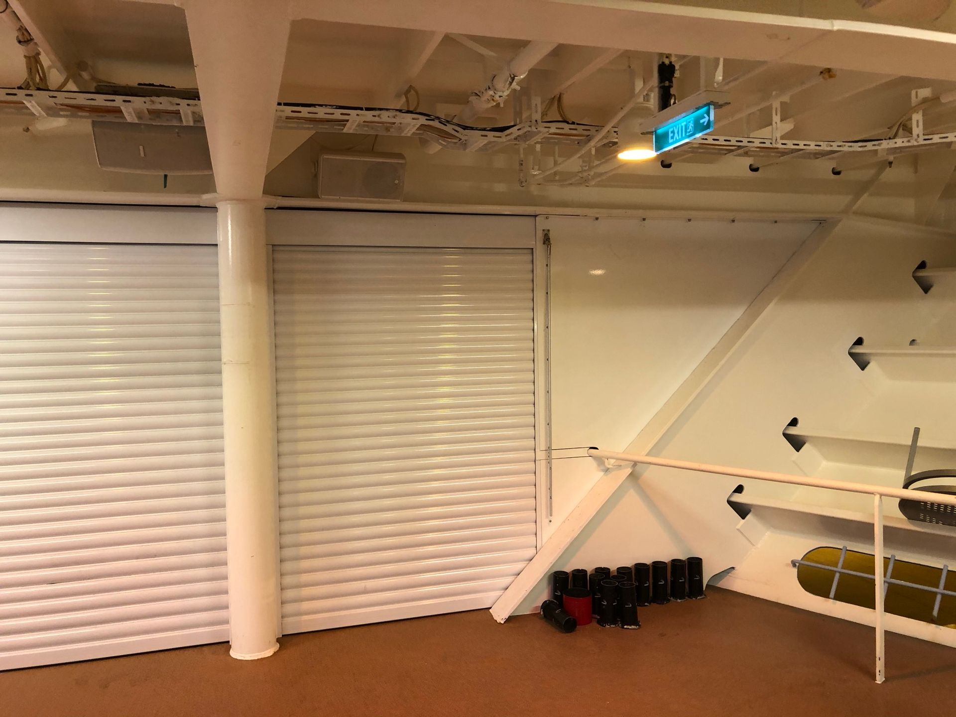 Empty retail interior with white blinds, shelves, and stacked black boots on the floor