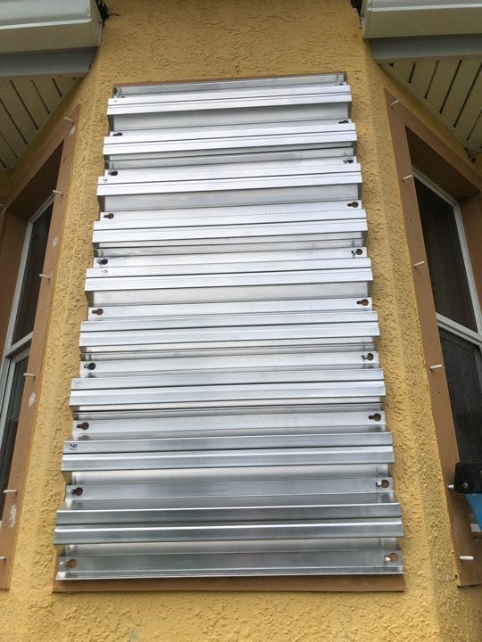 Stack of silver metal slats leaning against a yellow stucco wall on a stairway landing