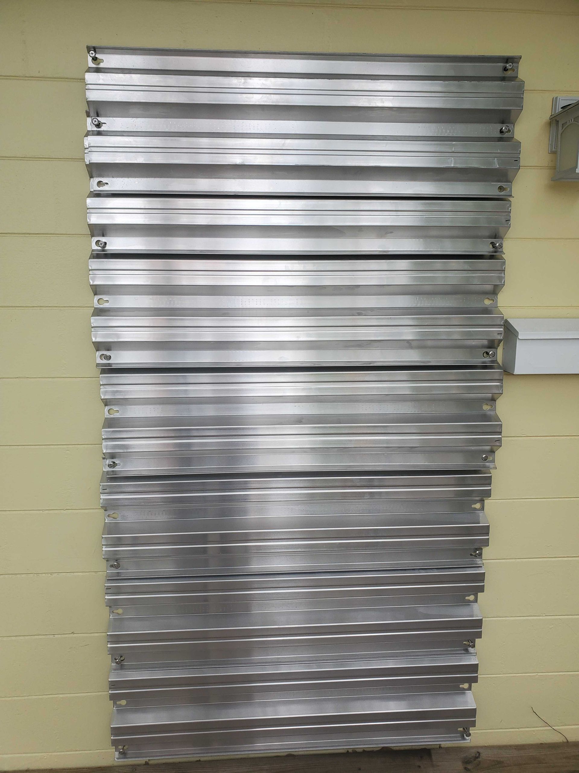 Stack of silver metal sheets leaning against a beige wall.