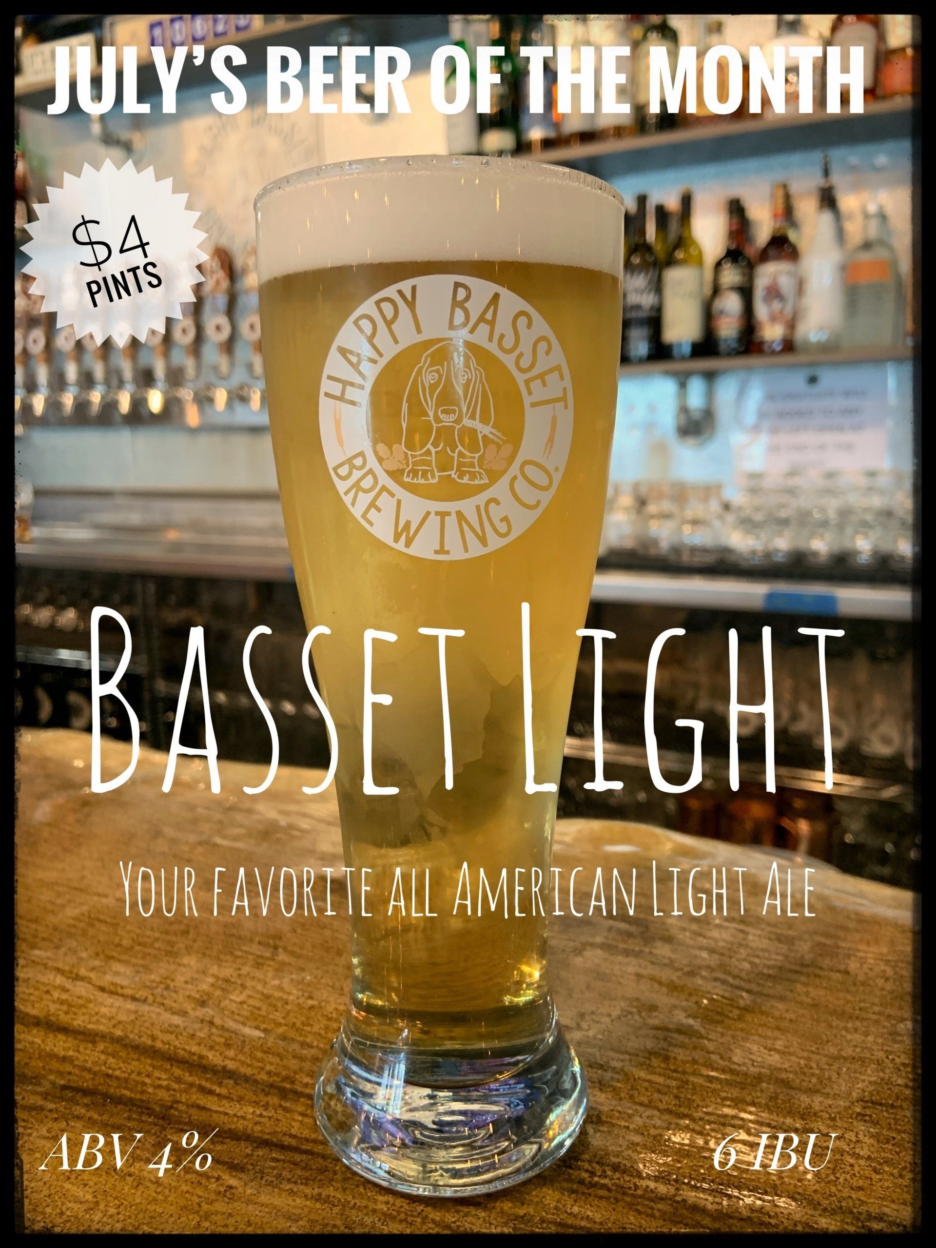 Glass of Bassett Light beer, July's beer of the month, $4.00, light ale from Happy Basset Brewing Co. with a bar background.