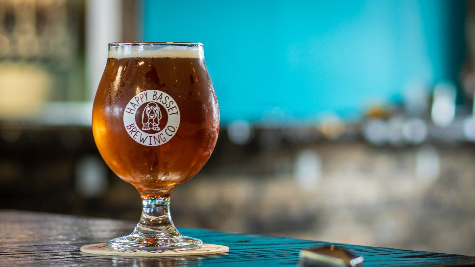 Beer glass on a bar with a logo, blurred background with blue wall and bar fixtures.