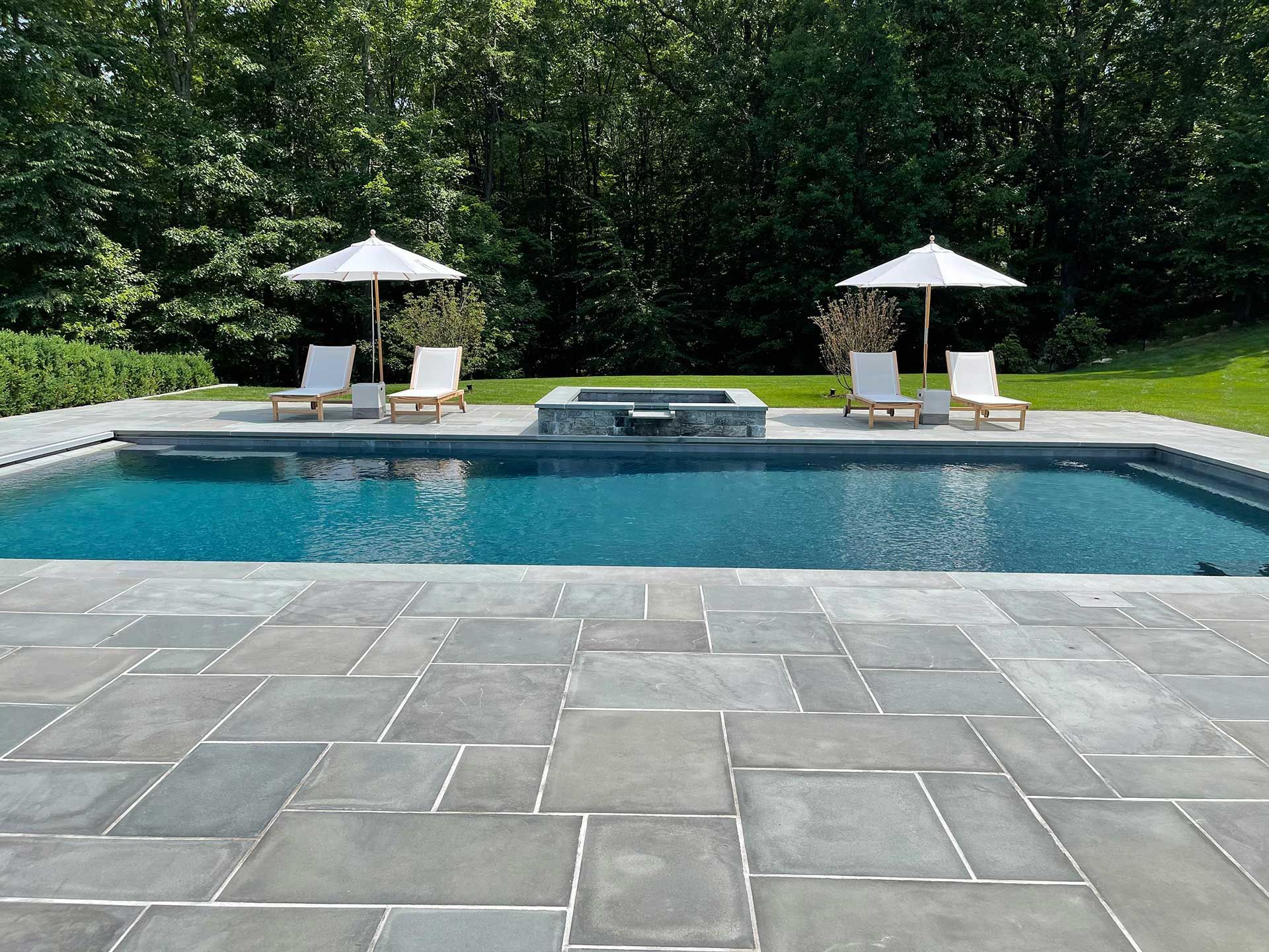 a large swimming pool surrounded by chairs and umbrellas