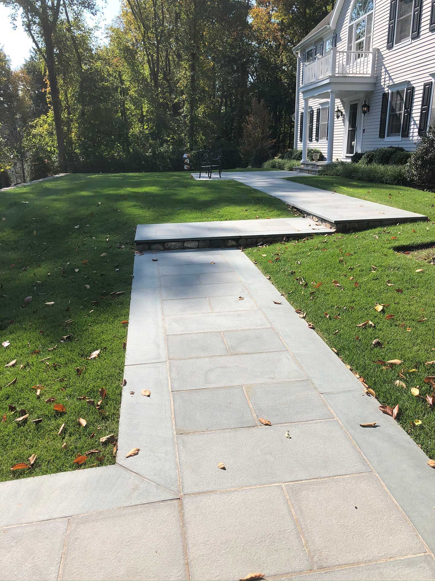 a walkway leading to a house with a lush green lawn