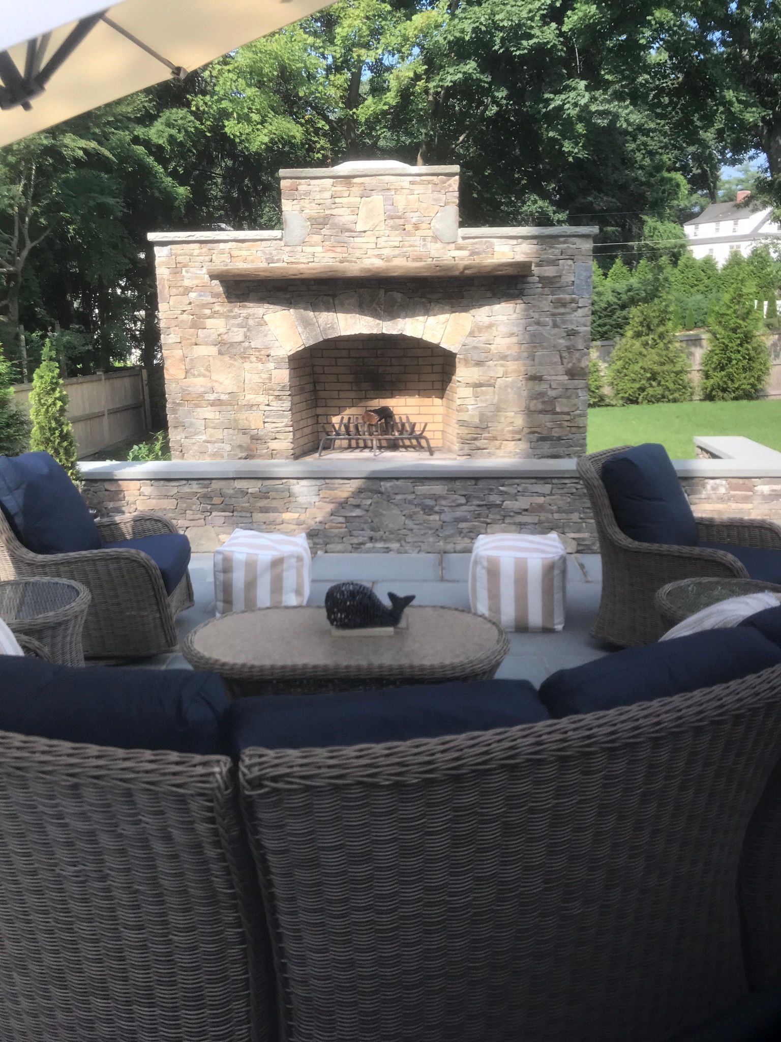 a patio with wicker furniture and a stone fireplace