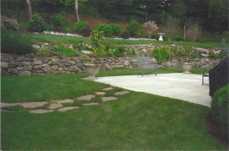 A lush green lawn with a stone wall in the background