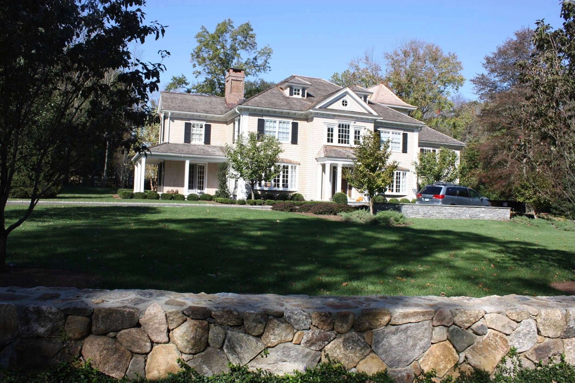 A large white house with a stone wall in front of it
