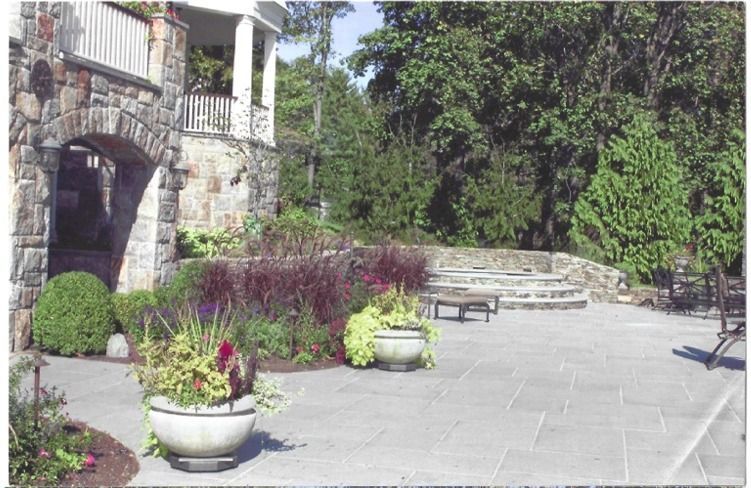 A patio with potted plants in front of a stone building