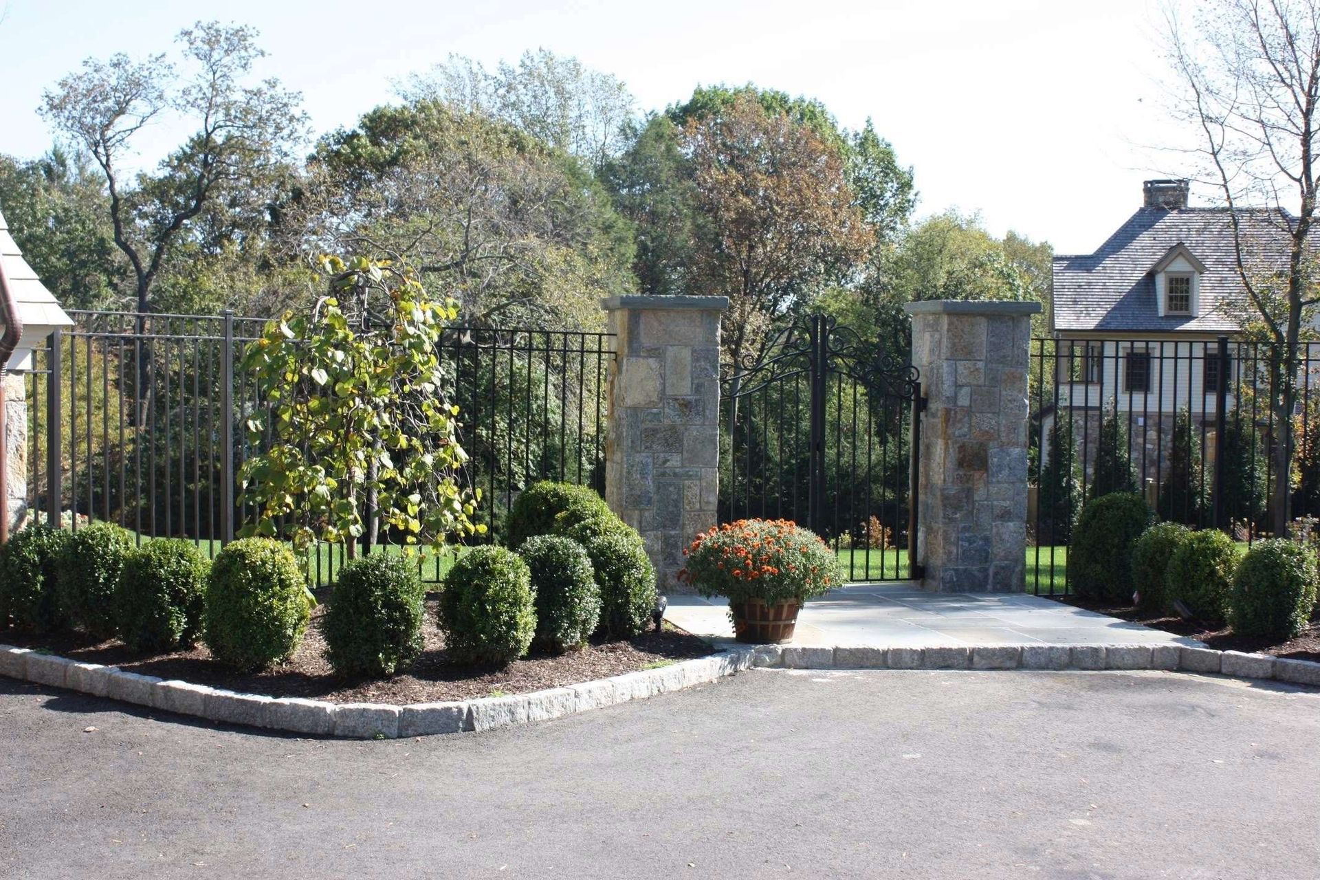 A fenced in area with bushes and trees in front of a house