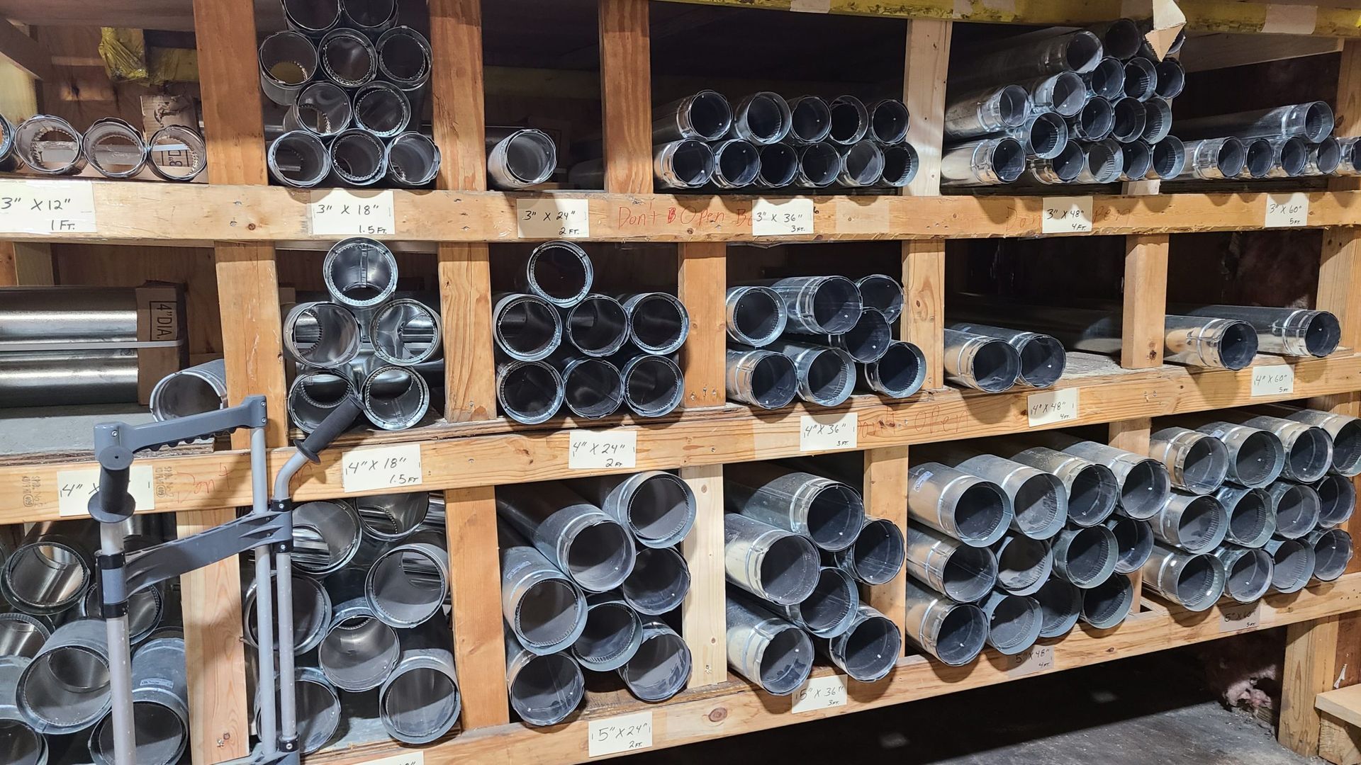 A bunch of pipes are stacked on top of each other on a wooden shelf.