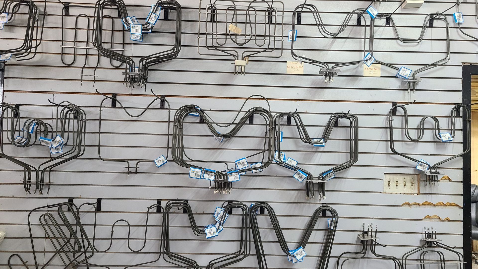 A wall with a bunch of wire sculptures hanging on it.