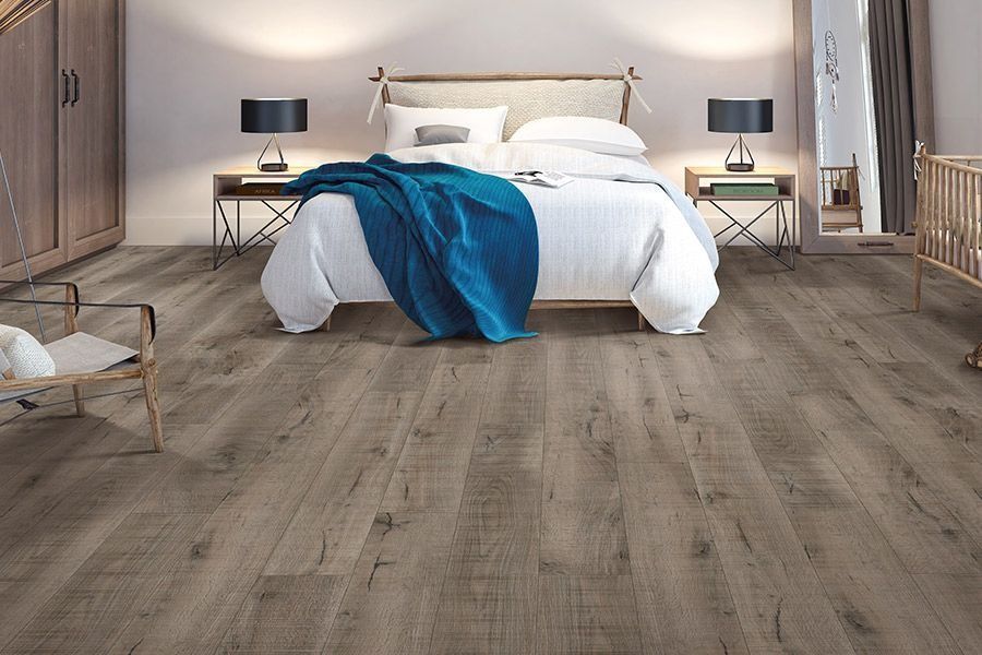 A bedroom with hardwood floors and a bed with a blue blanket on it.