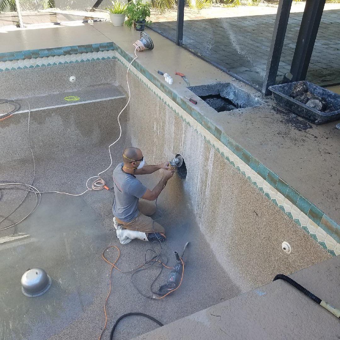 a man is working on the side of a swimming pool