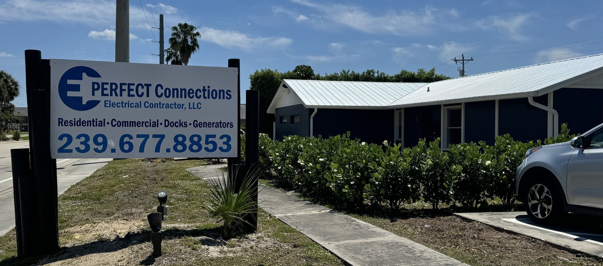 A car is parked in front of a perfect connections sign