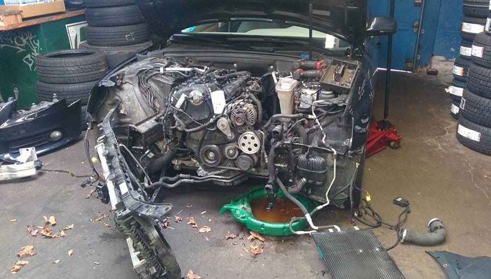 The engine of a car is being worked on in a garage.