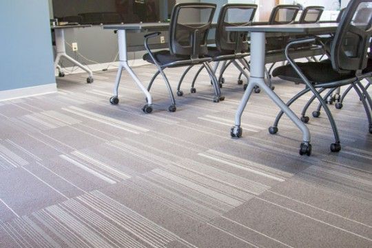 Empty office meeting room with rolling chairs and a conference table on a striped carpet