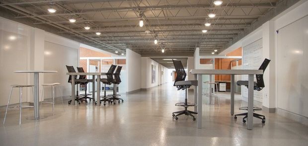 Bright modern open office with desks, stools, and overhead lighting