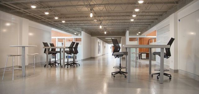 Bright modern open office with desks, stools, and overhead lighting