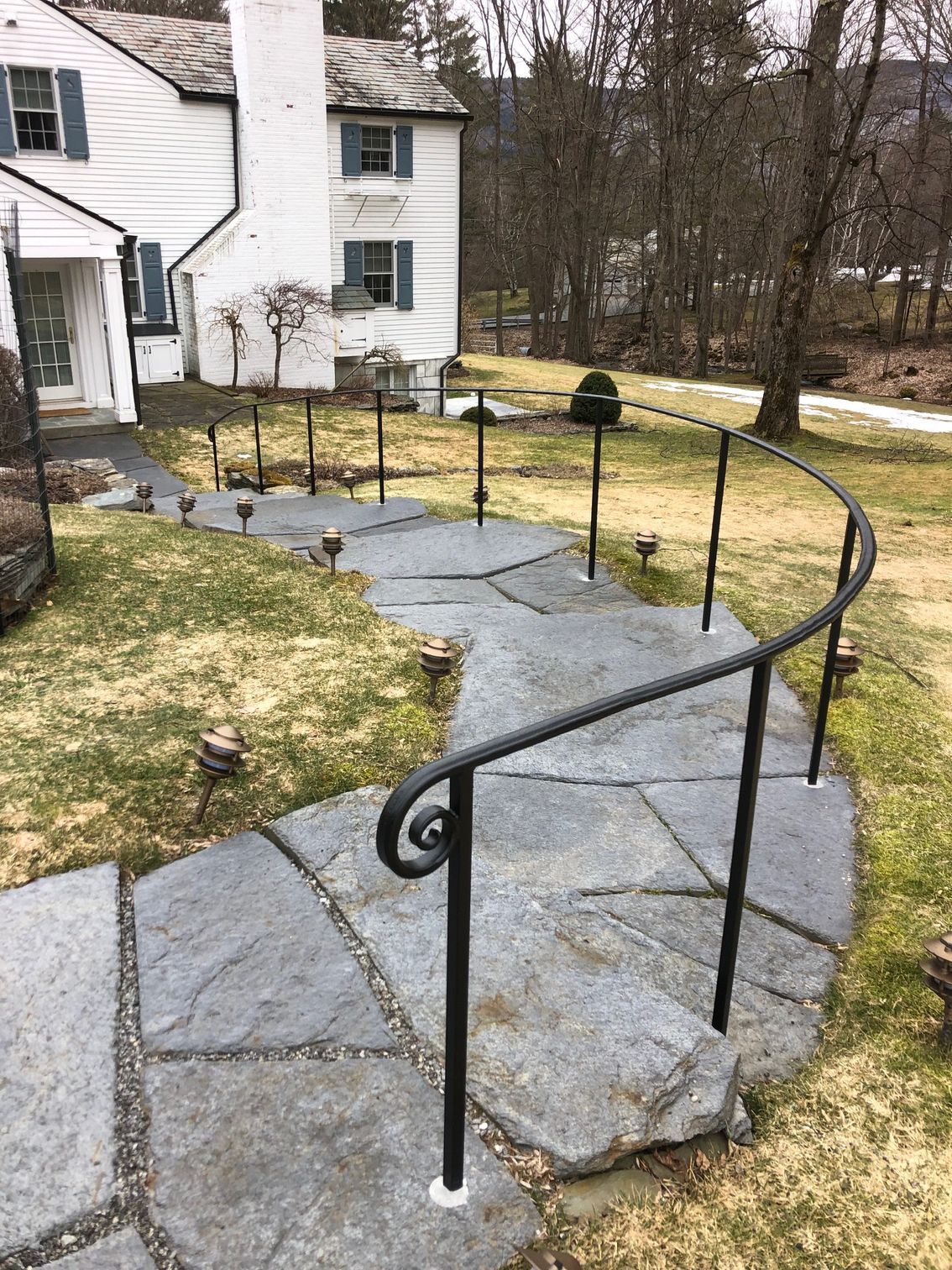 A stone walkway with a wrought iron railing leading to a house.