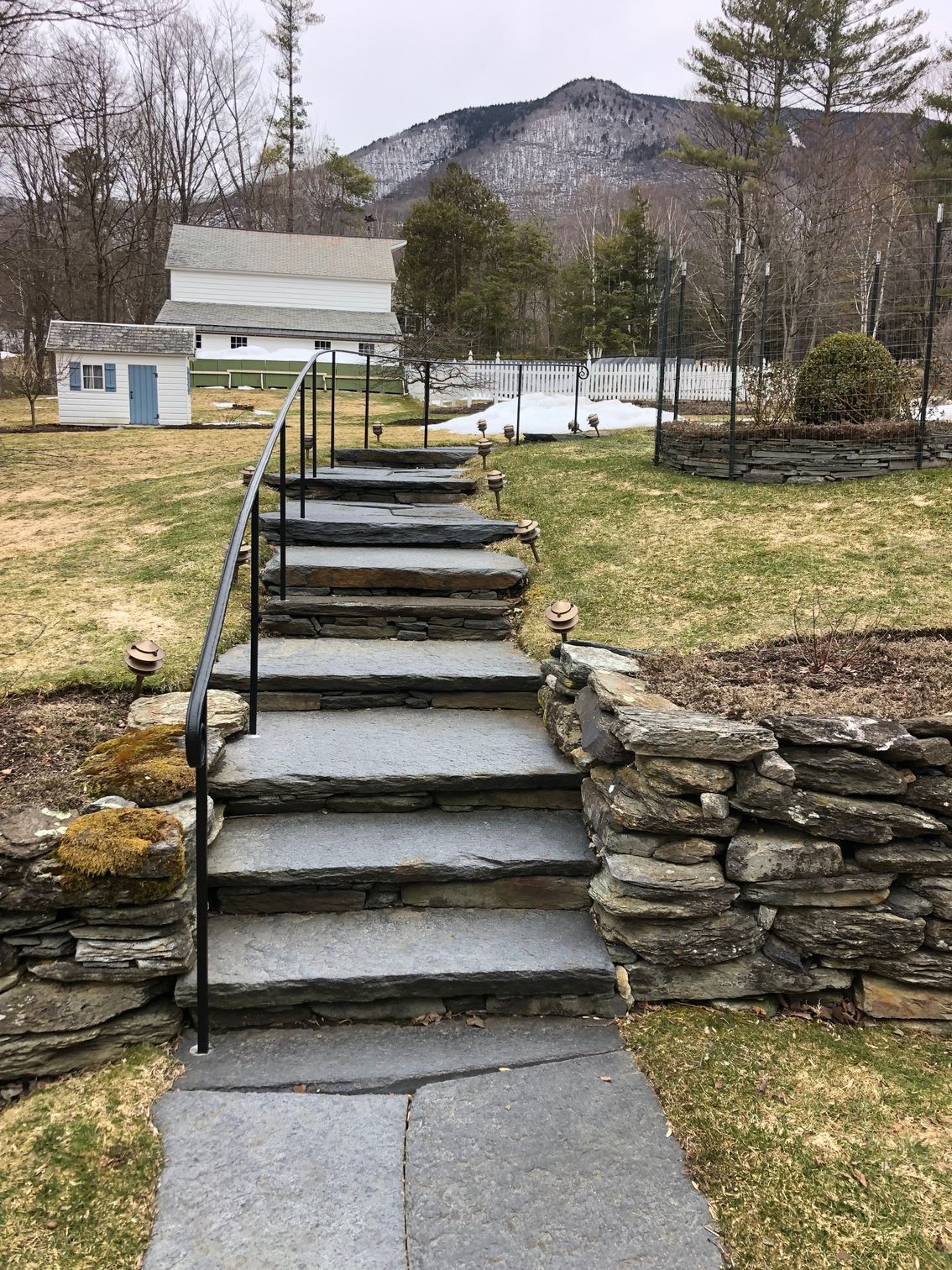 A set of stone stairs leading up to a stone wall in a yard.