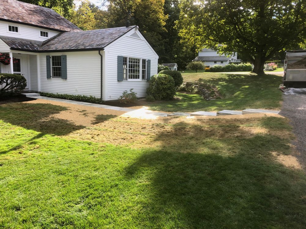 Lawn in front of a white house with a partially brown, dying area of grass.