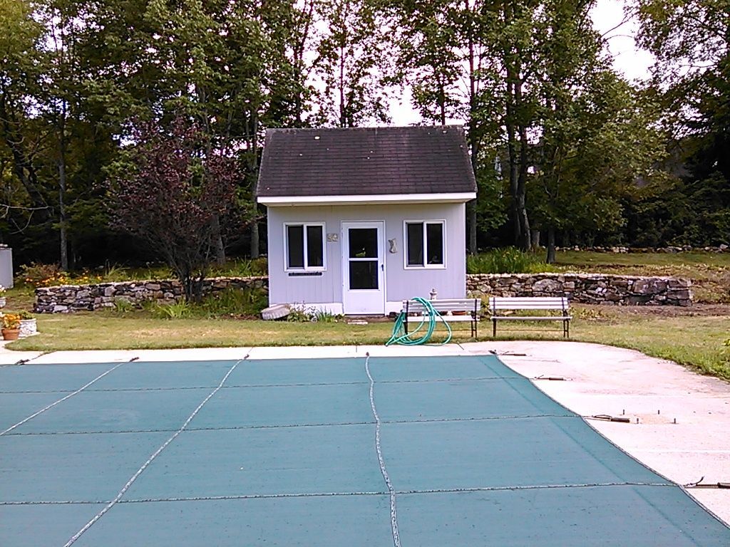 A small white house sits next to a swimming pool