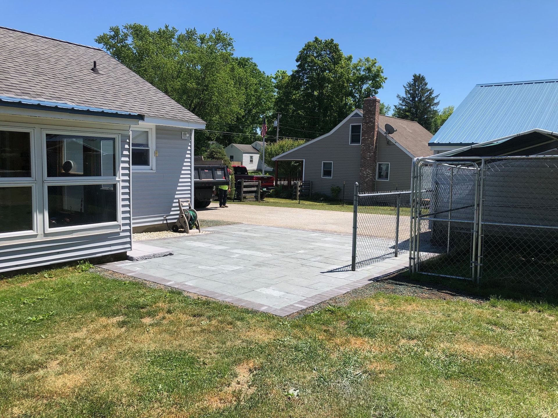 A fenced in yard with a house and a shed in the background.